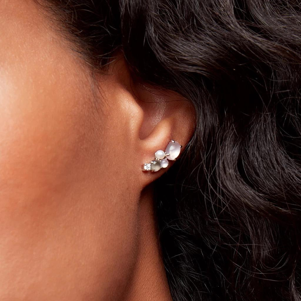 Close-up of a woman's ear wearing a silver cluster stud earring with soft white moonstone, pearl, and crystal accents.