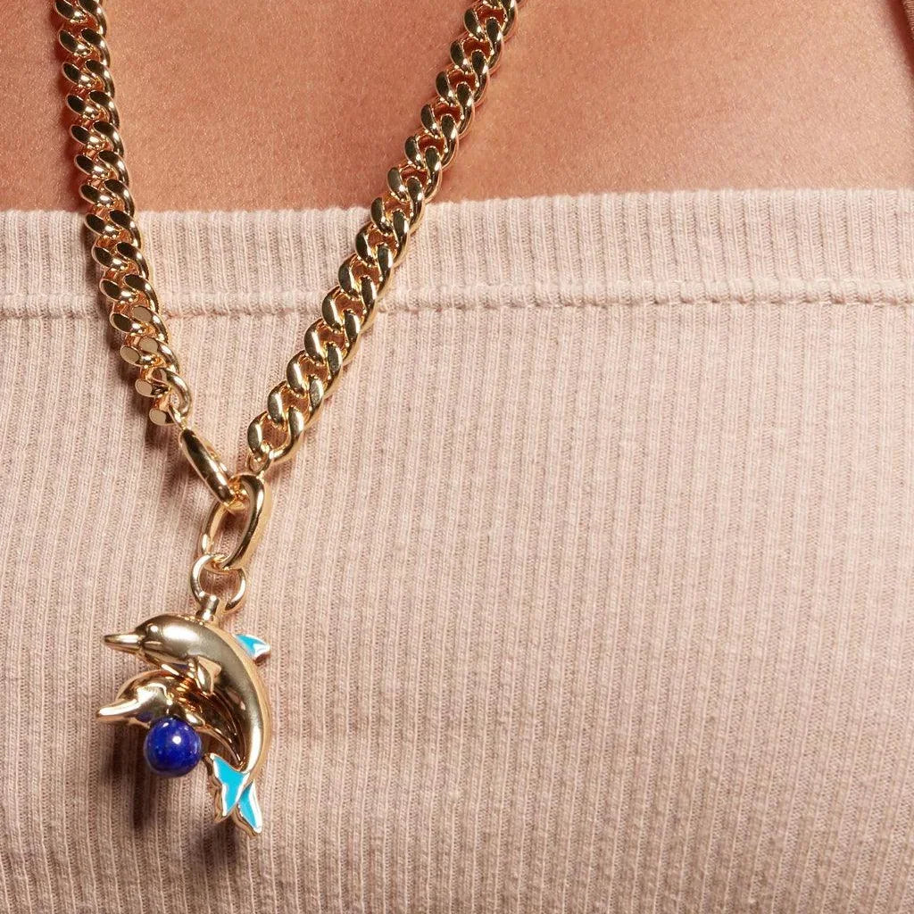 Gold dolphin charm necklace with lapis detail, styled on a model wearing a ribbed top.