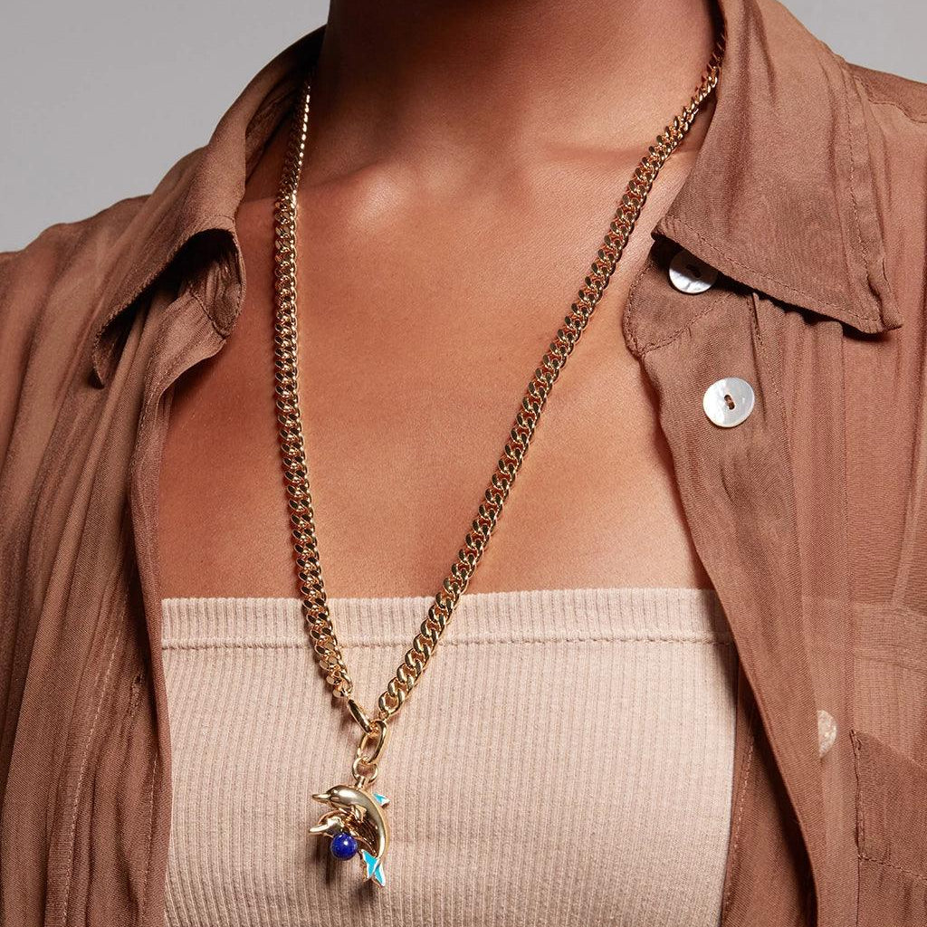 Gold dolphin charm necklace with lapis detail worn over brown sheer shirt