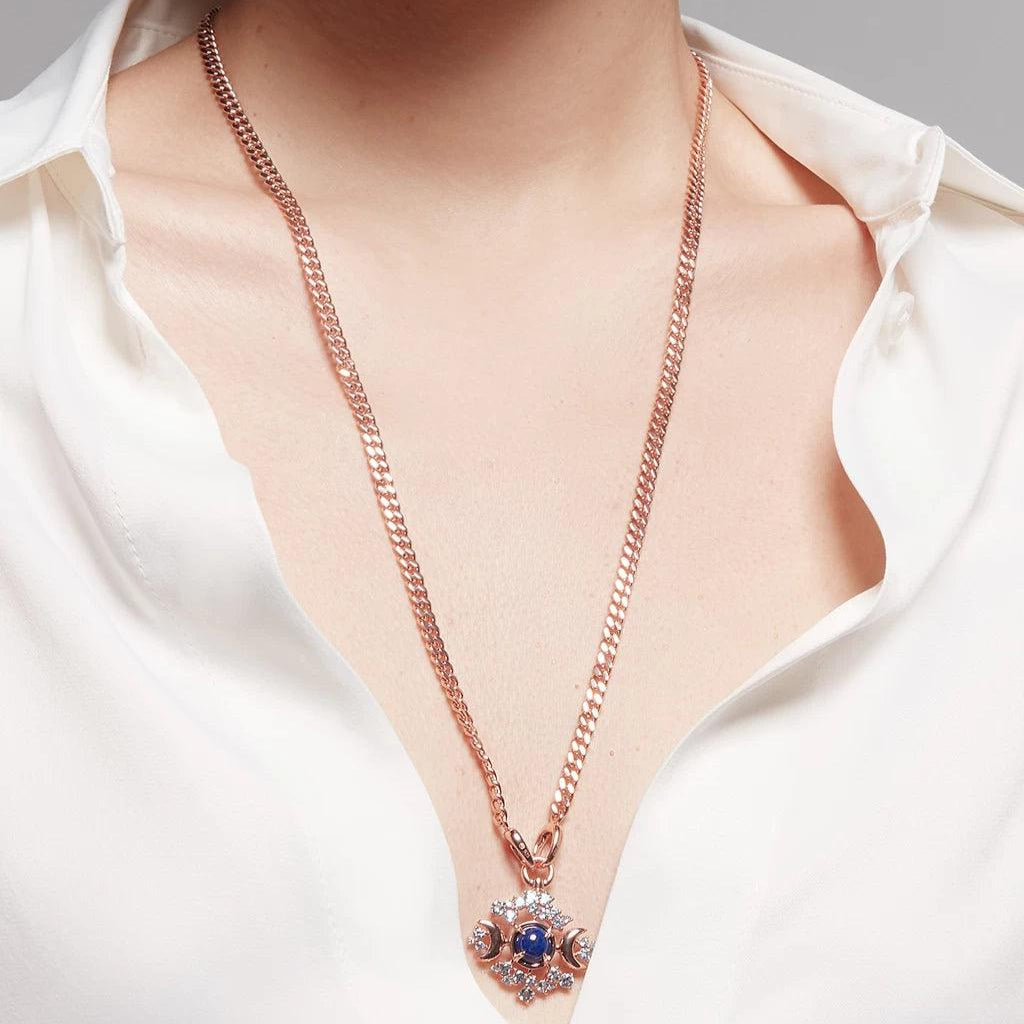 Elegant long rose gold chain with blue gemstone celestial moon charm styled on white blouse.