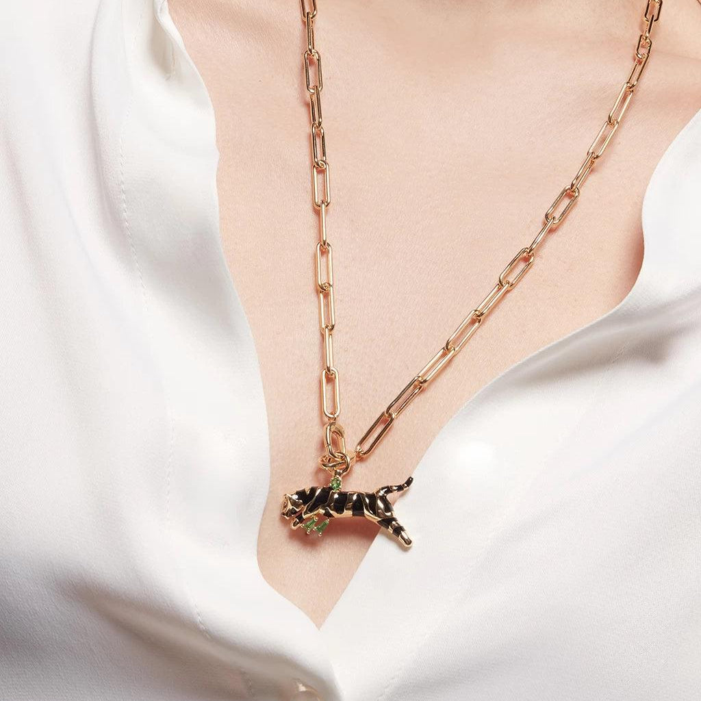 Long gold chain necklace with black panther charm worn over white blouse.
