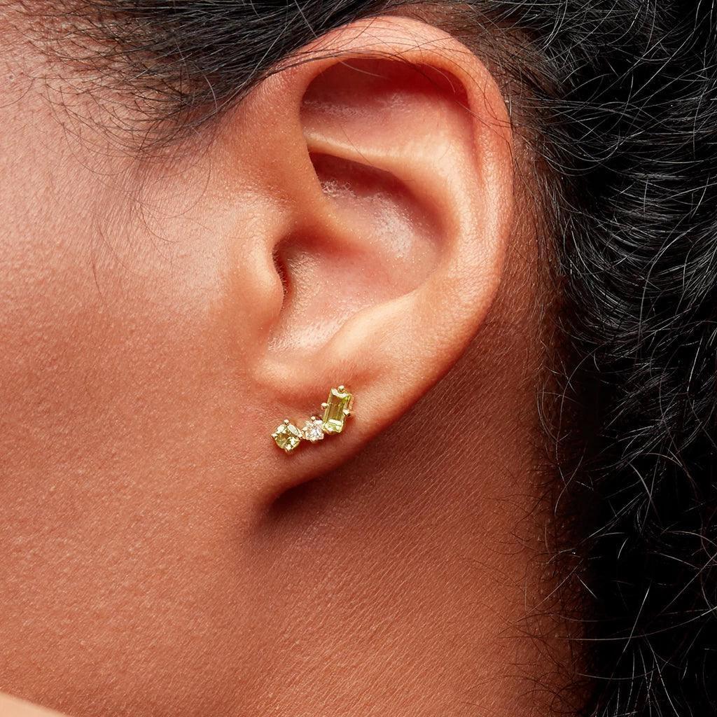 Minimalist green peridot and diamond cluster studs styled on ear for everyday wear.