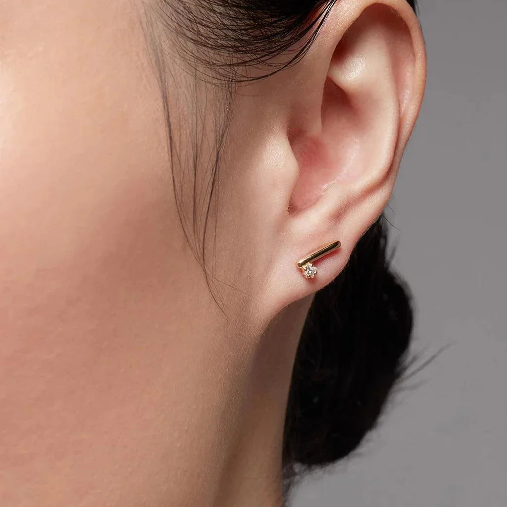 Yellow gold bar and diamond stud earring on ear close-up