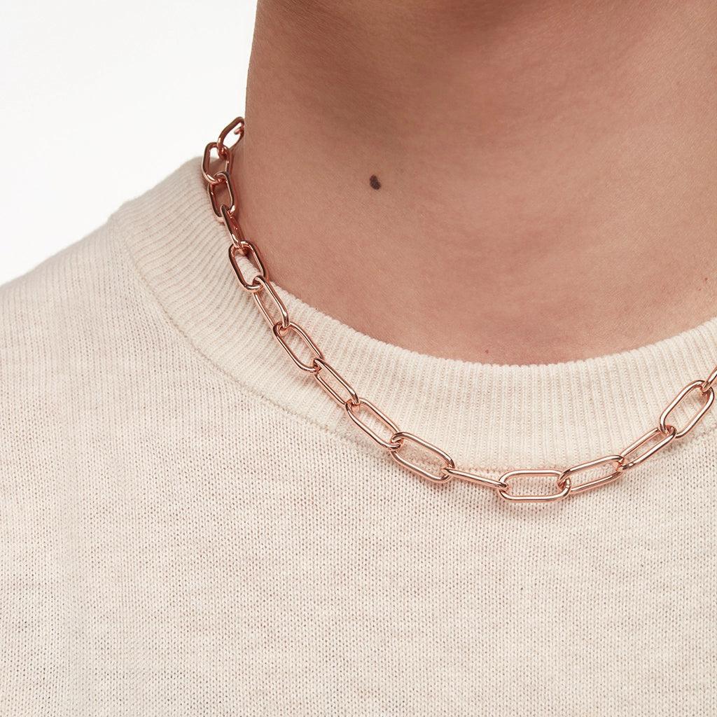 Minimal rose gold chain necklace worn over cream sweater