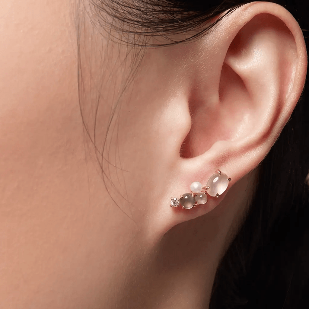Delicate cluster stud earring with moonstone, pearl, and crystal on a woman's ear, showing elegant minimalist styling.