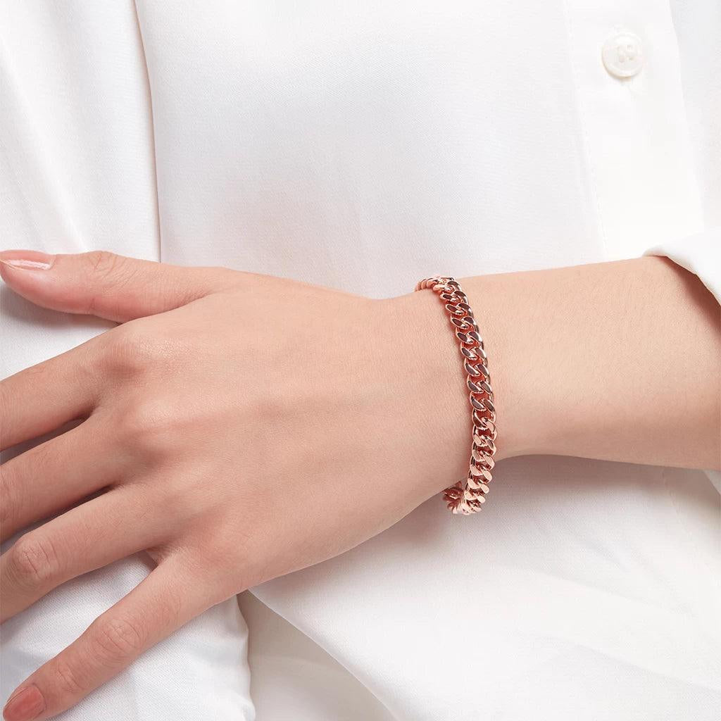 Minimalist rose gold Cuban link bracelet worn on wrist with white blouse.