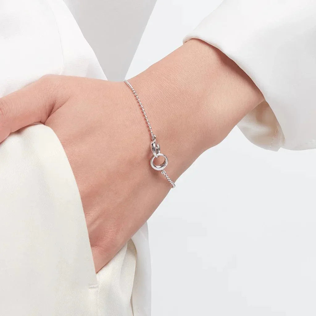 Minimalist silver chain bracelet on wrist with circular clasp detail