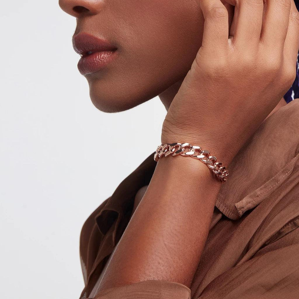 Chunky rose gold chain bracelet on wrist styled with neutral outfit