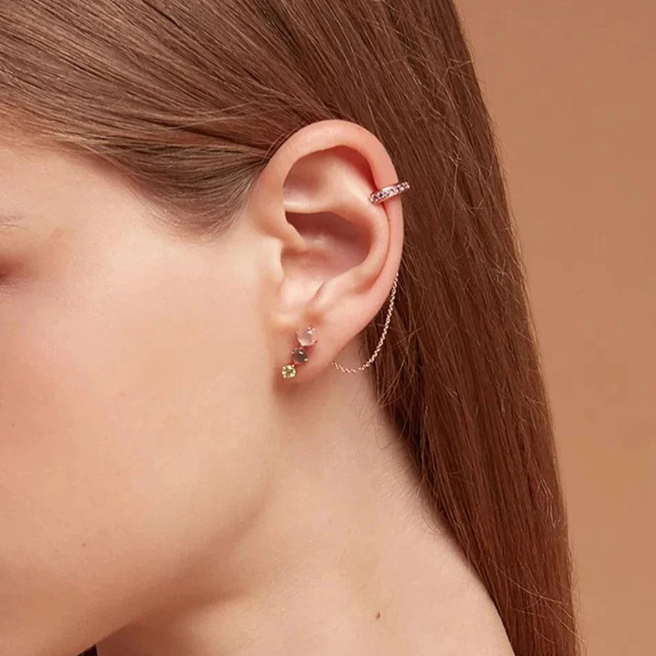 Rose gold ear cuff with pink stones and chain, paired with multicolor gemstone stud earrings on model