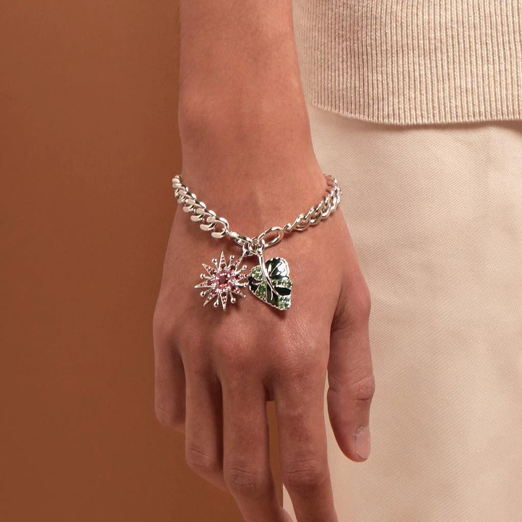 Bold silver chain bracelet with pink starburst and green leaf charms