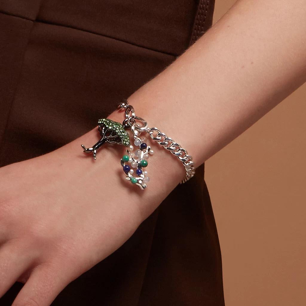 Silver charm bracelet with green tree and colorful coral charms on wrist