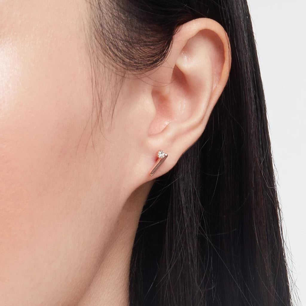 Close-up of minimalist rose gold bar stud earring with single diamond on ear