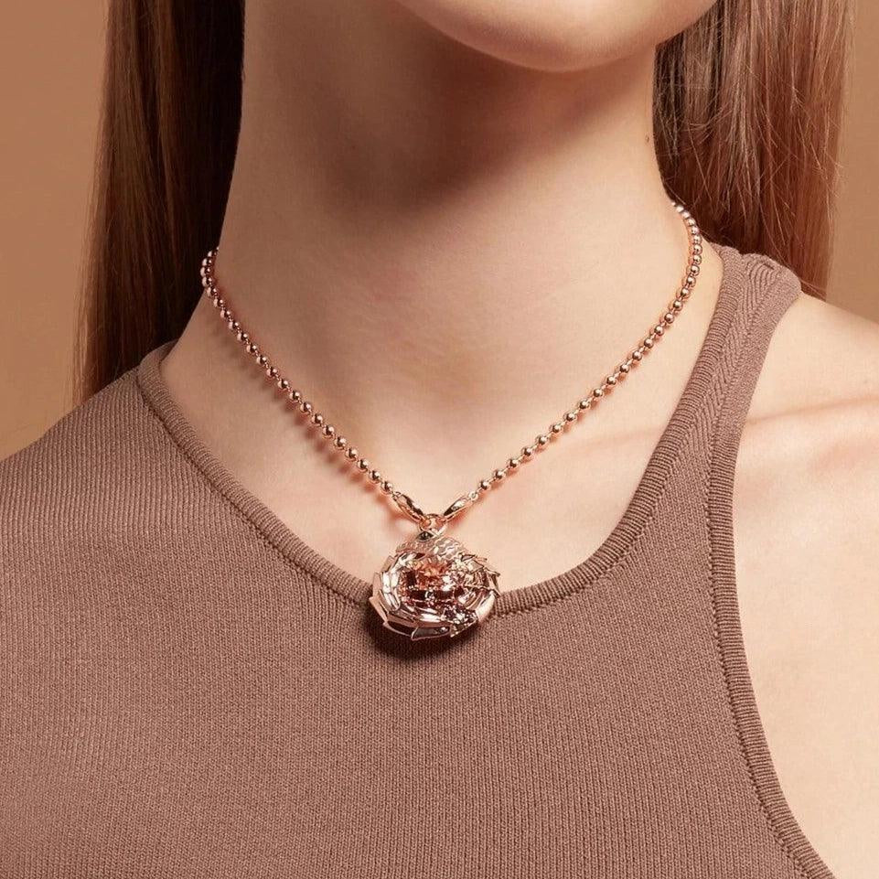 Rose gold ball chain necklace styled with an intricate dragon charm on female model