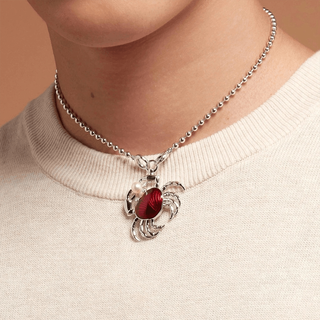 Silver necklace featuring a crab charm with red enamel center.