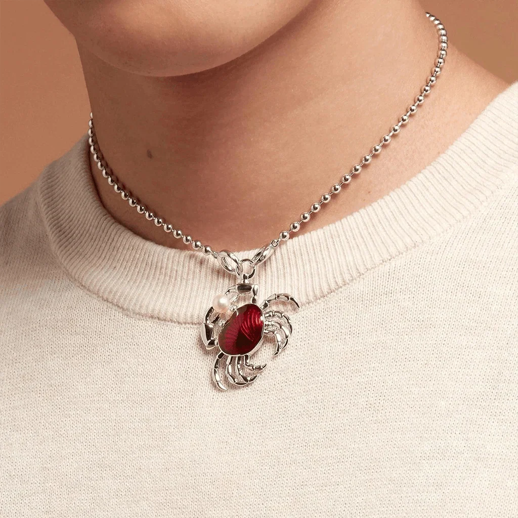 Silver necklace featuring a crab charm with red enamel center.