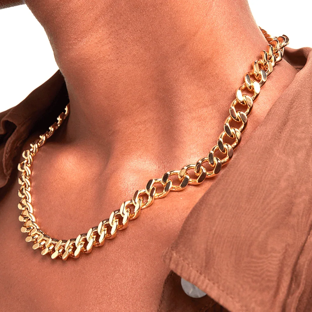 Bold gold Cuban chain necklace styled on bare neck with brown shirt
