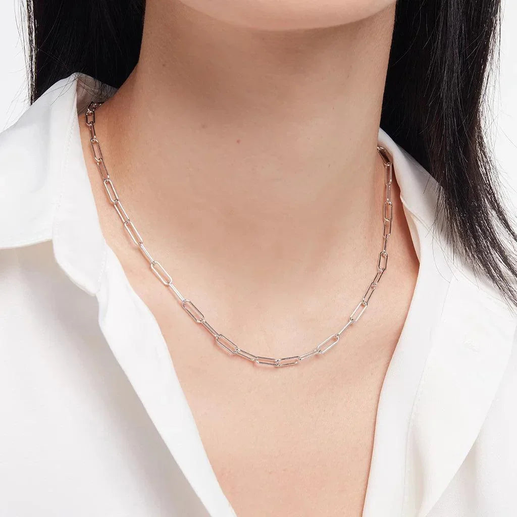 Minimalist silver paperclip chain necklace on model in white shirt