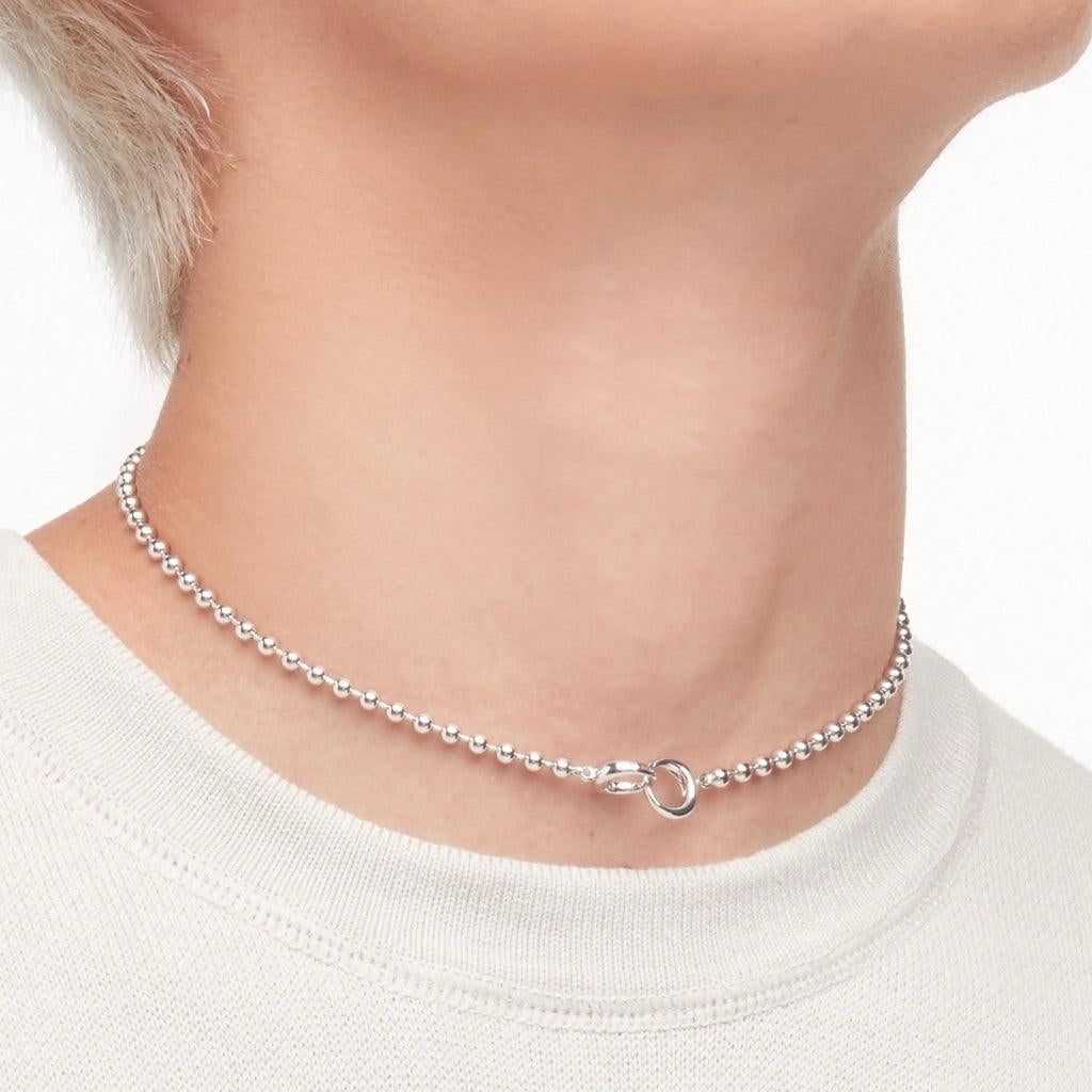 Minimalist silver choker necklace with secure clasp styled on a model in a crew neck.
