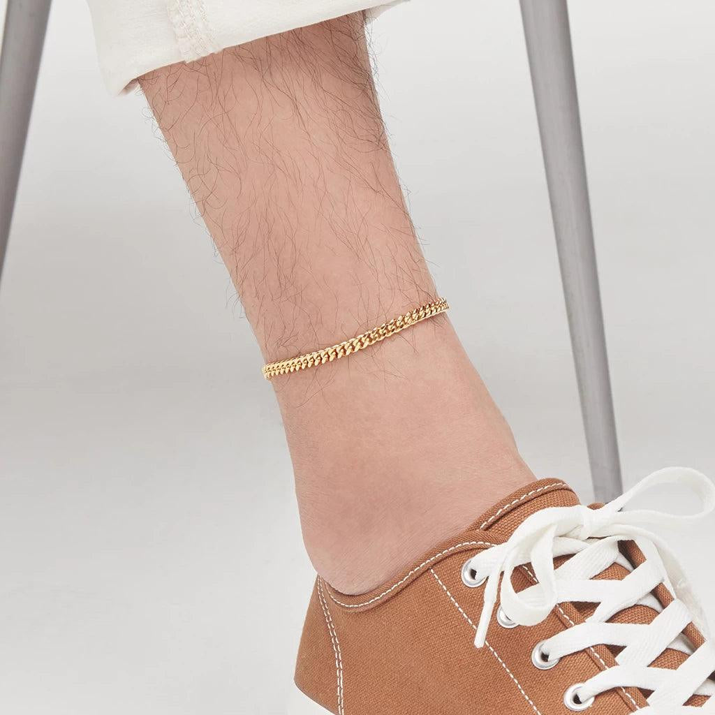 Simple gold anklet chain styled on male model with sneakers.
