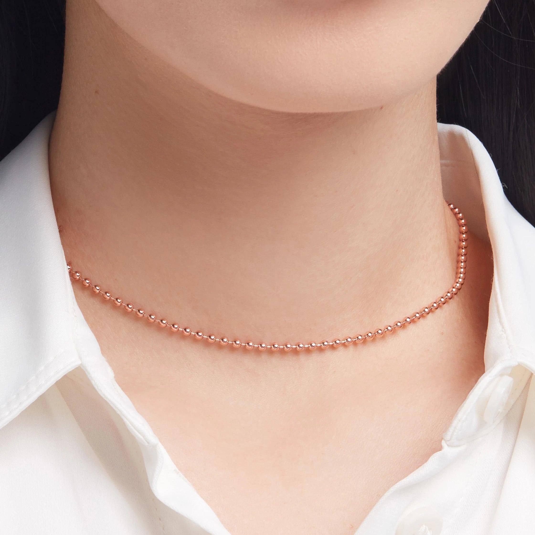 Delicate rose gold choker necklace styled elegantly with a crisp white shirt.