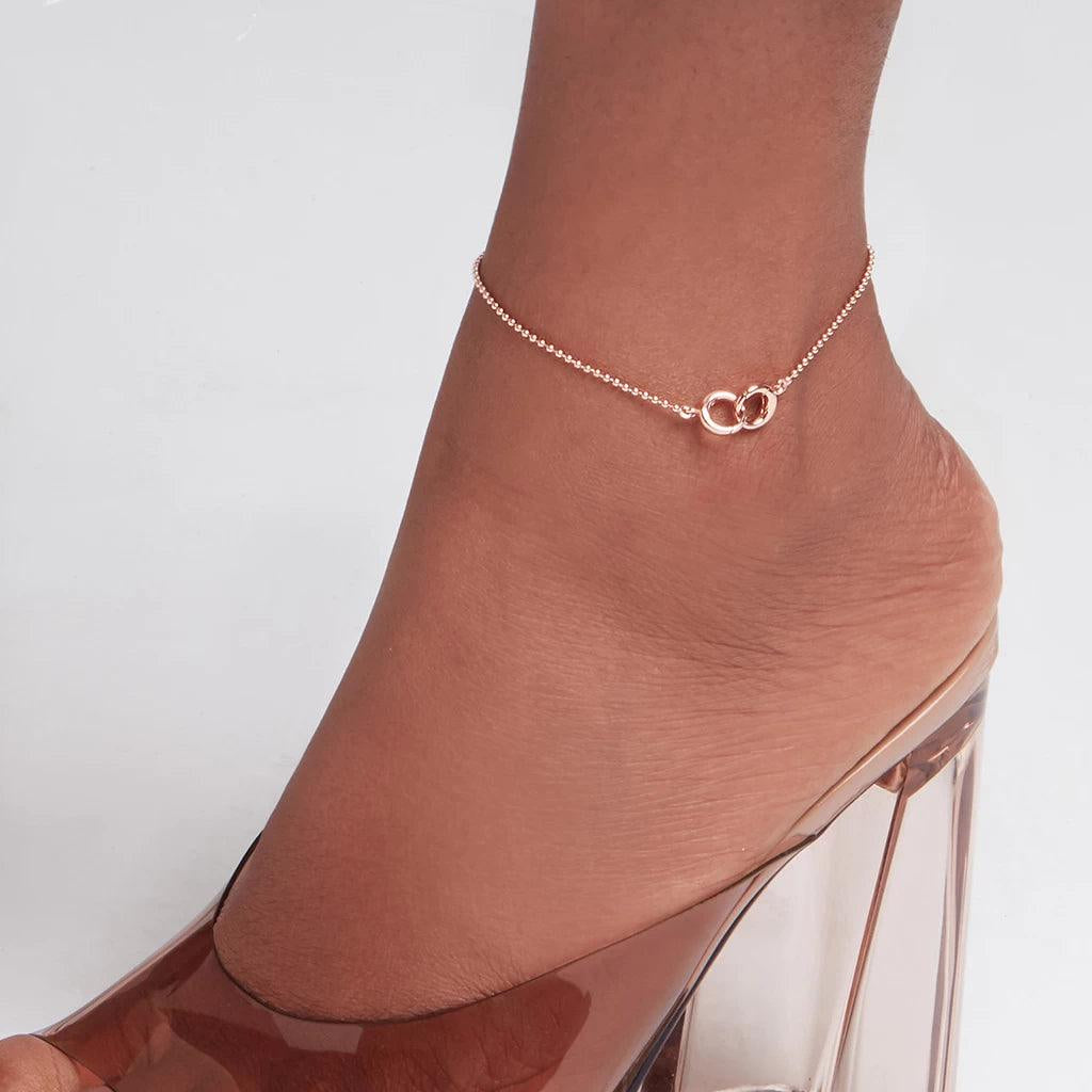 Minimal rose gold anklet with interlocking rings on woman’s ankle