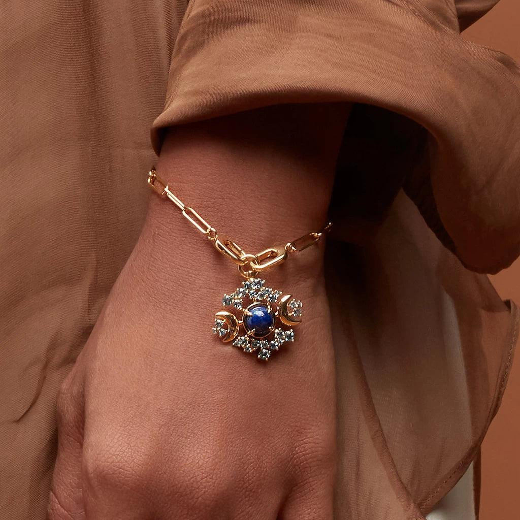 Elegant gold charm bracelet with blue gemstone and intricate moon design.