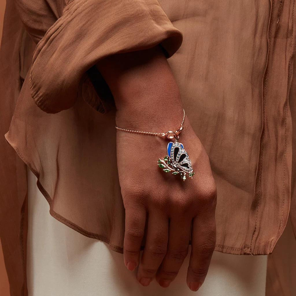 Rose gold charm bracelet with detailed butterfly charm worn with sheer sleeve
