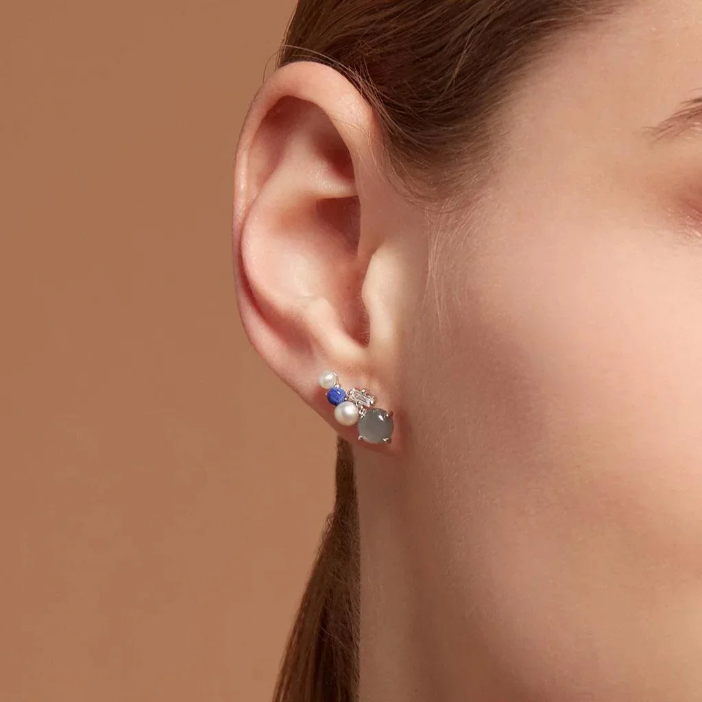 Silver cluster stud earring with pearls and blue stones on ear, modern mixed-stone design.