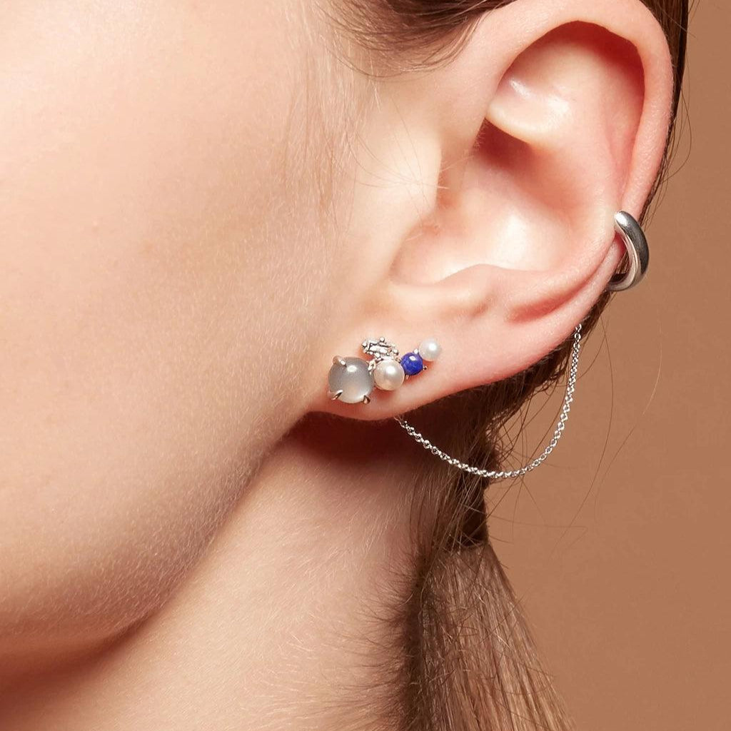 Silver cluster earring with pearls, blue accents, and chain cuff detail, worn on ear.
