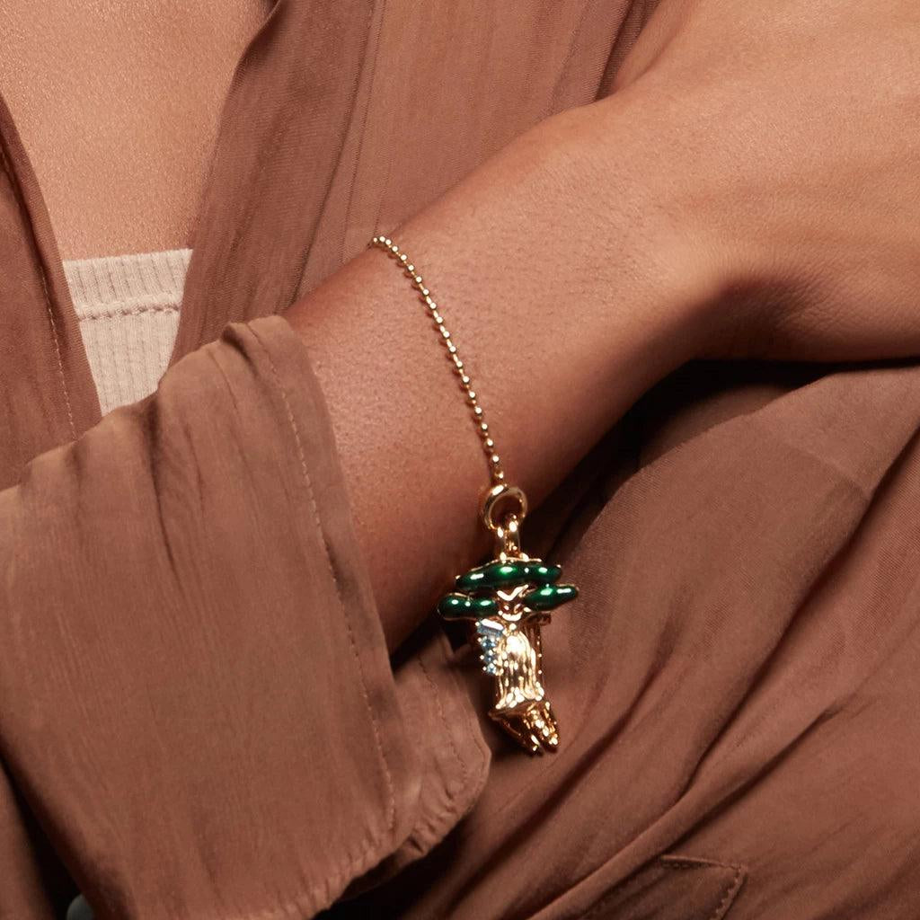 Gold beaded bracelet with detailed Baobab tree charm on model’s wrist