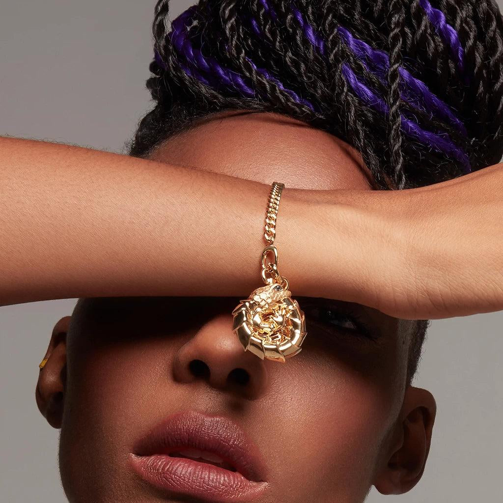 Bold gold bracelet with dragon charm styled on wrist, fashion statement piece.