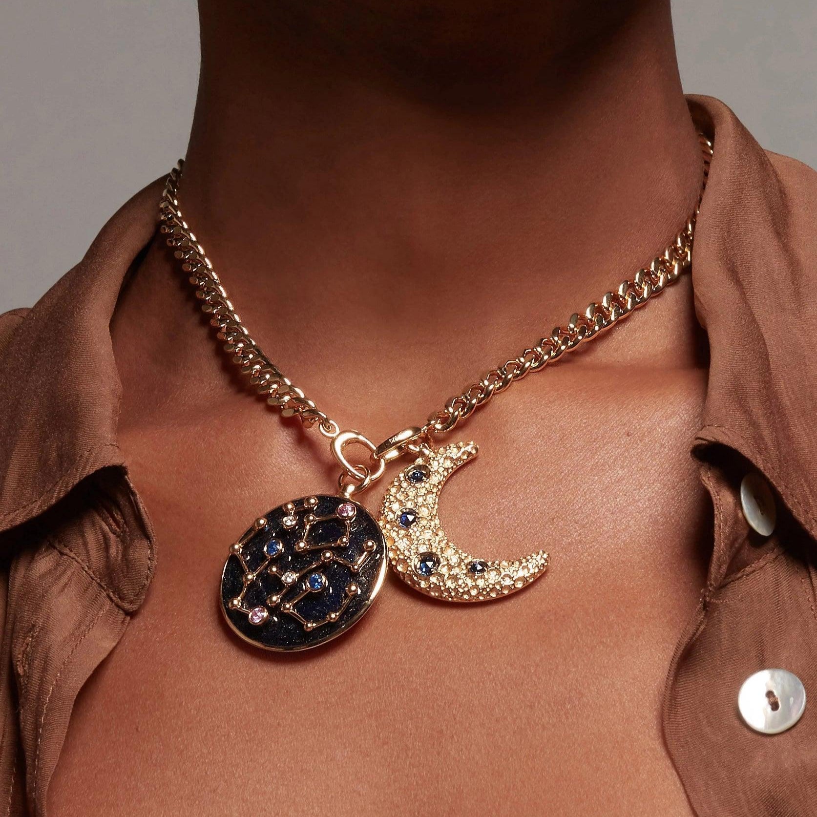 Close-up of a gold cuban chain necklace featuring crescent moon and constellation charms