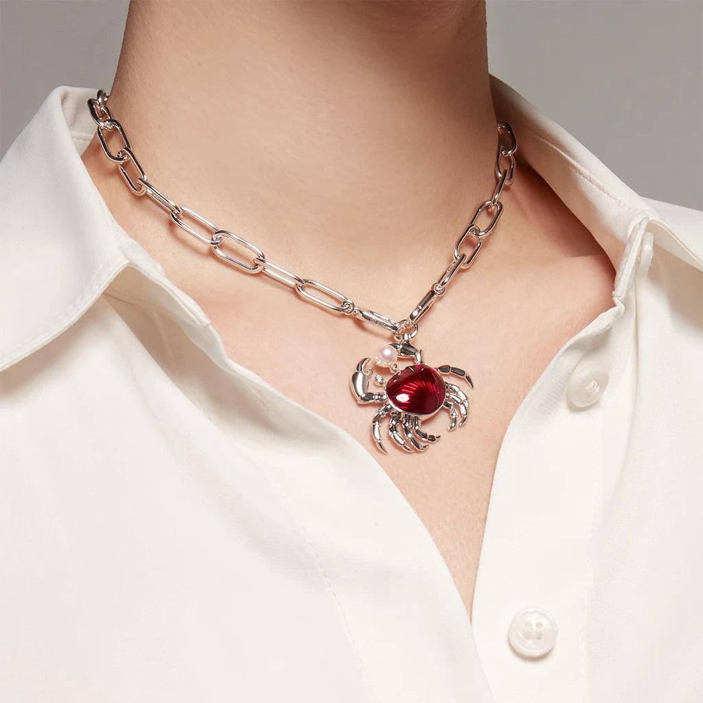 Chunky silver chain choker with red crab charm on model in white blouse