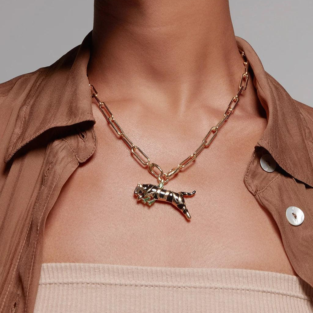 Gold chain necklace with black enamel panther pendant, styled on brown shirt.
