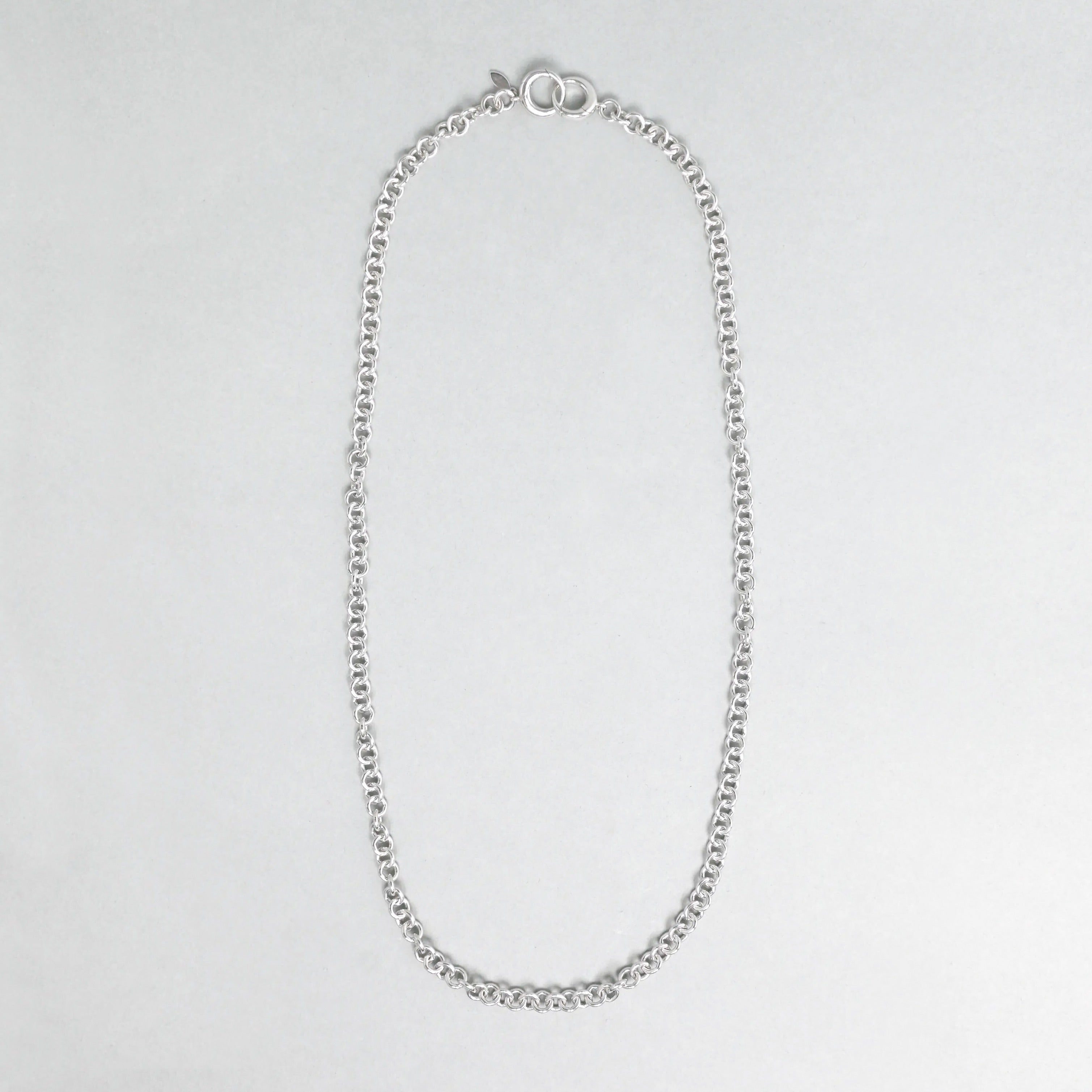 Silver chain necklace on a light gray background
