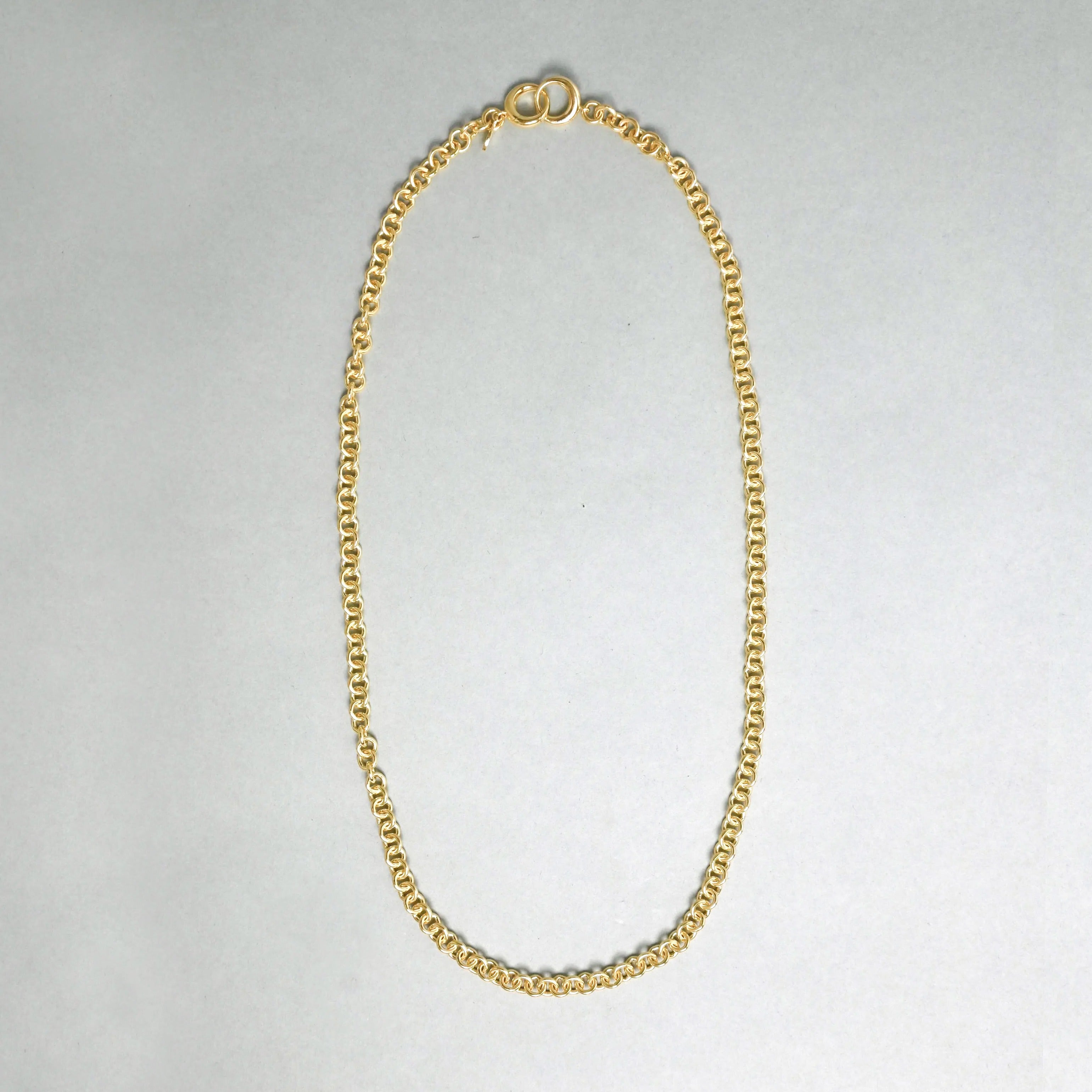 Gold chain necklace on a light gray background