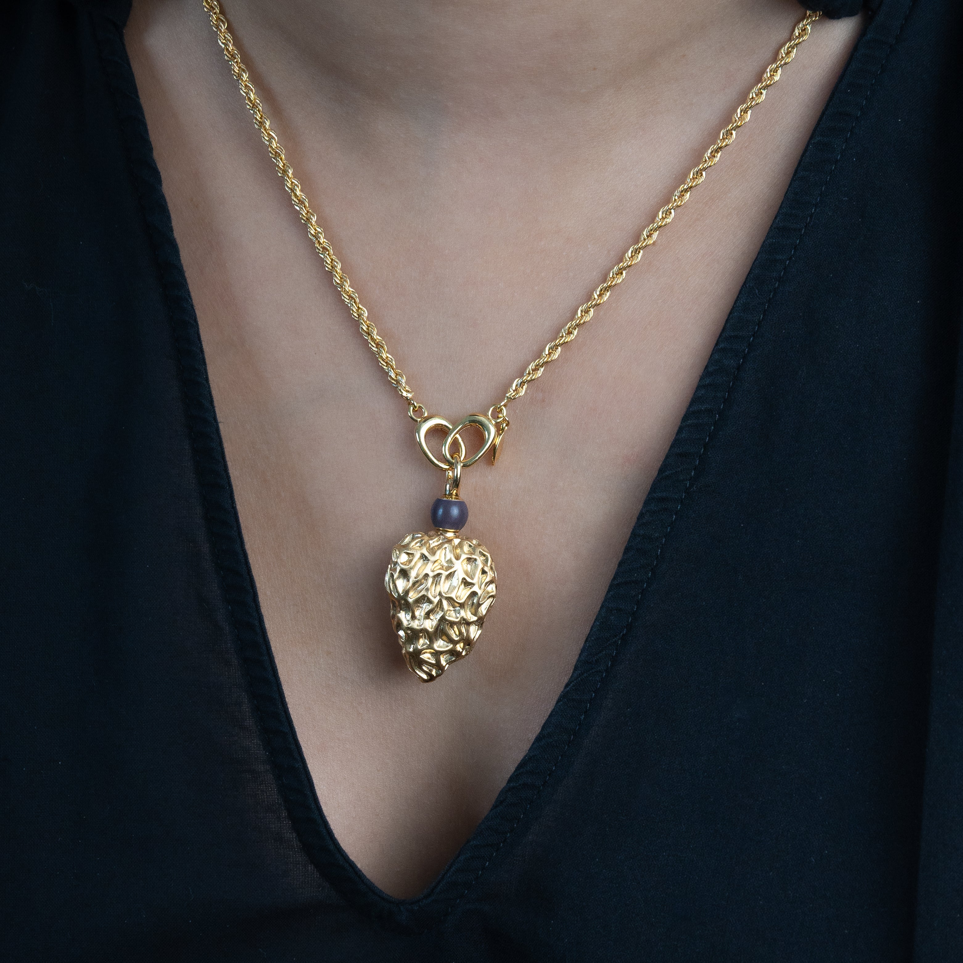 Gold necklace with a gold heart-shaped pendant worn by a person