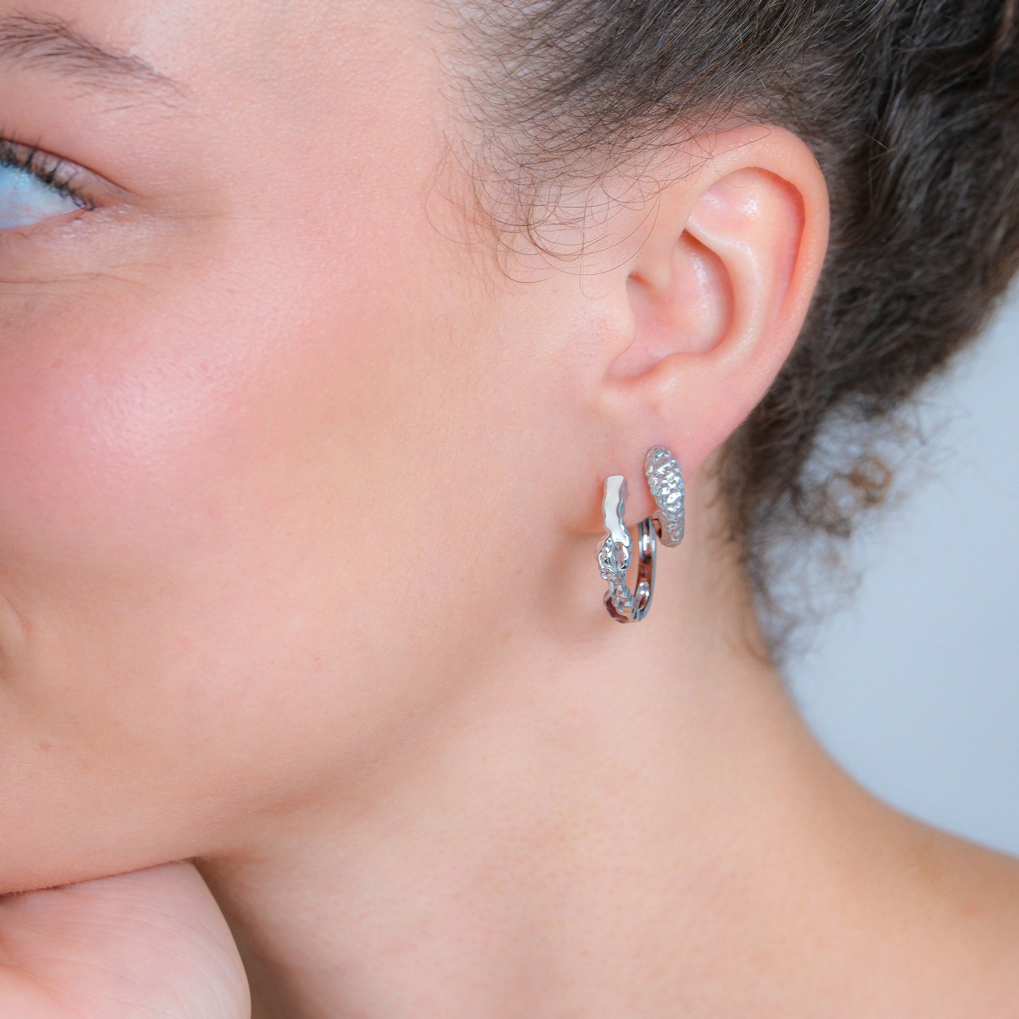 Close-up of a woman wearing silver hoop earrings.