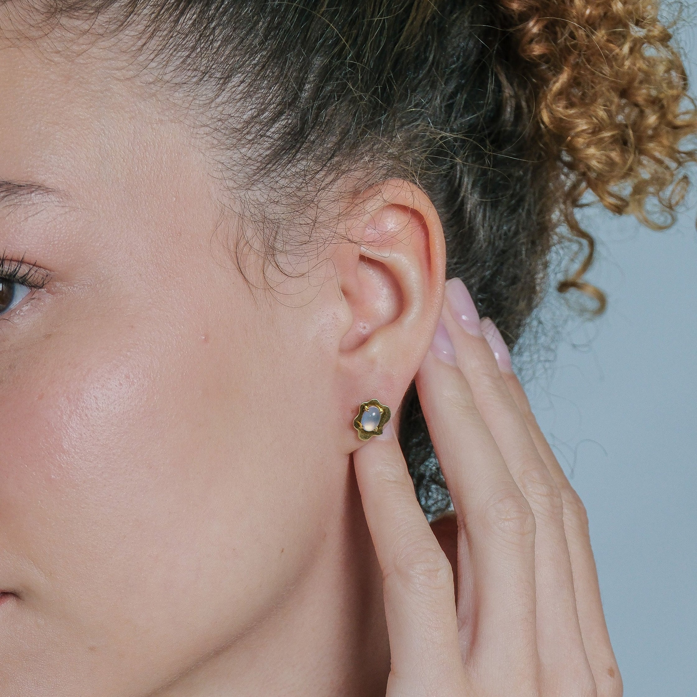 Woman wearing a stud with gemstone with a plain background