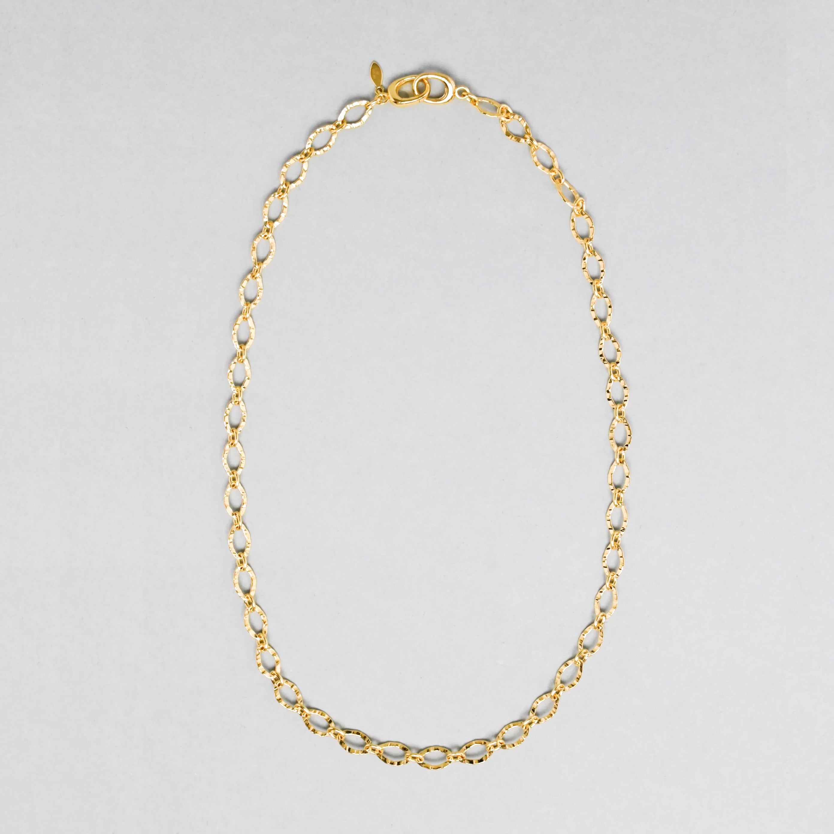 Gold chain necklace on a light gray background