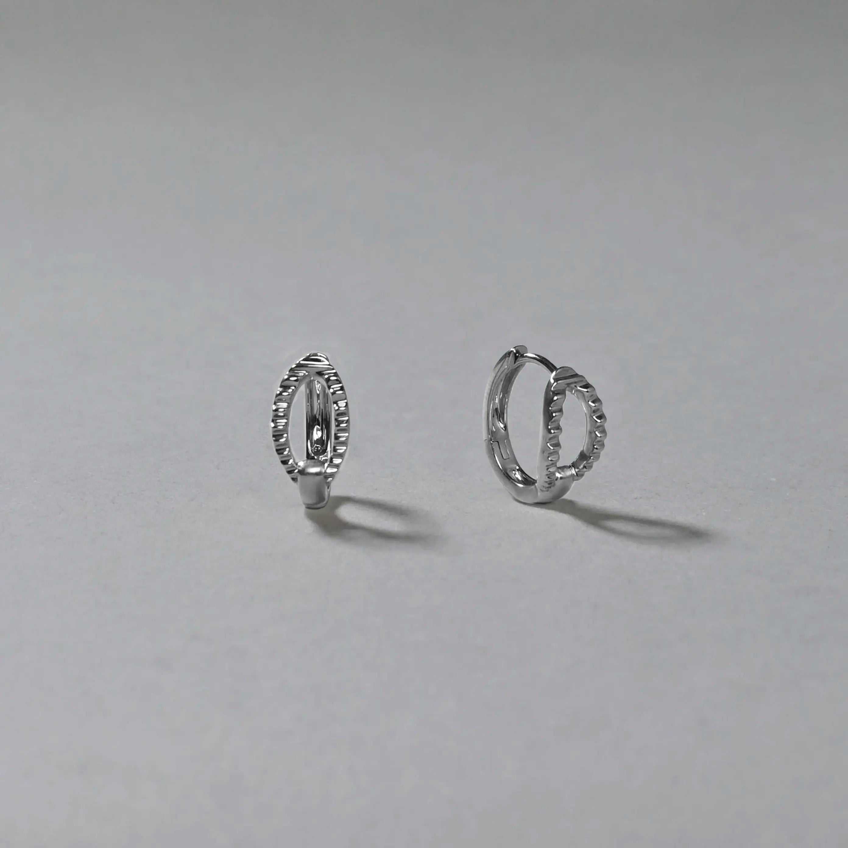Pair of silver hoop earrings on a gray background