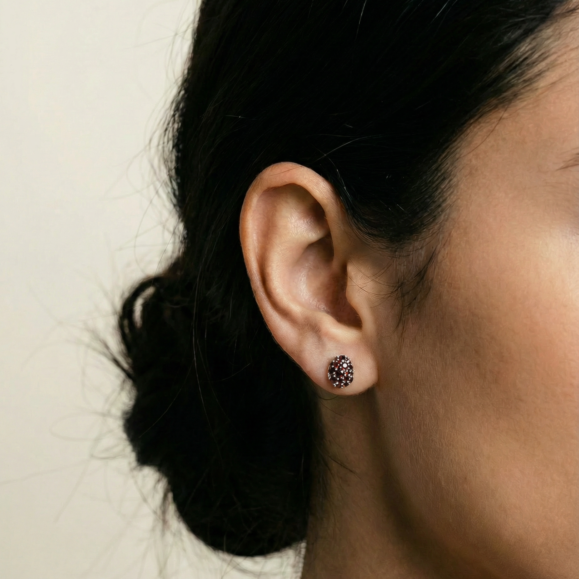 Close-up of an ear wearing a stud earring with a neutral background