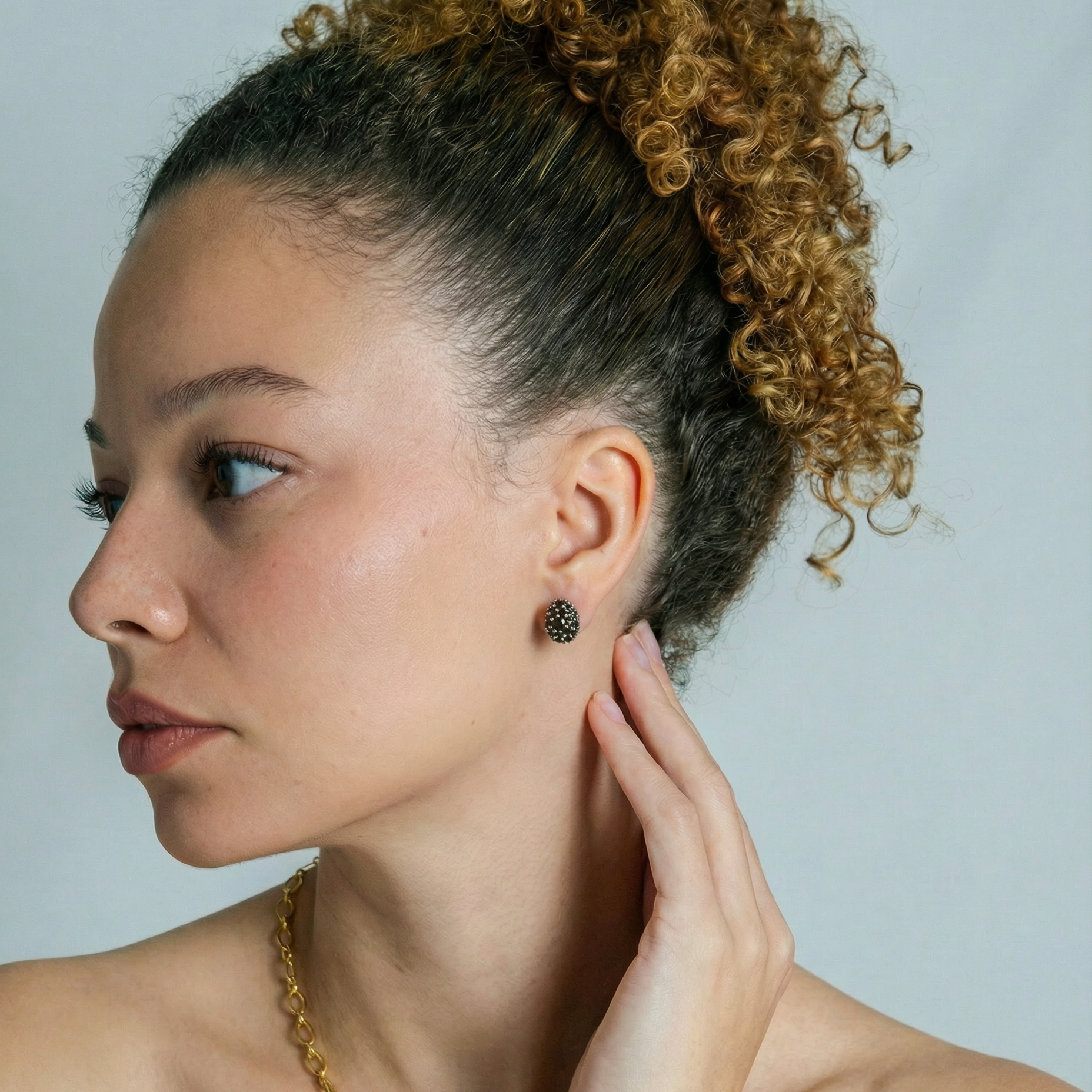 Woman with styled hair and earrings against a plain background