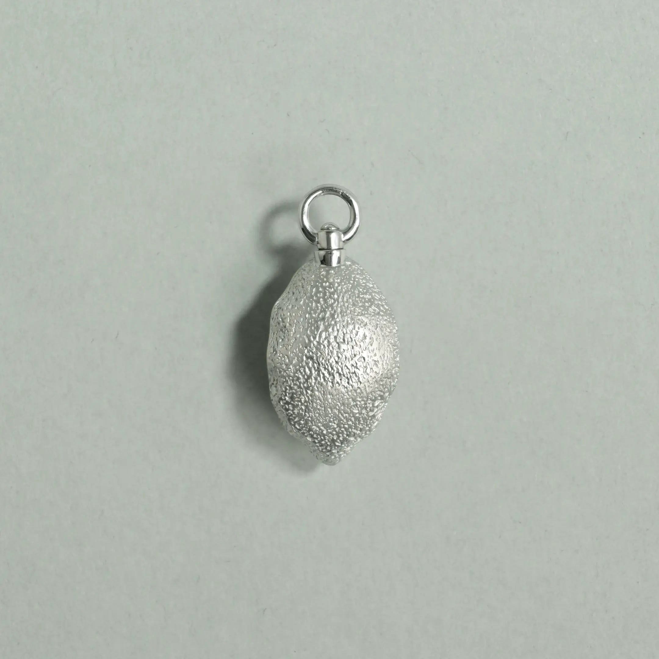 Silver textured pendant on a light gray background