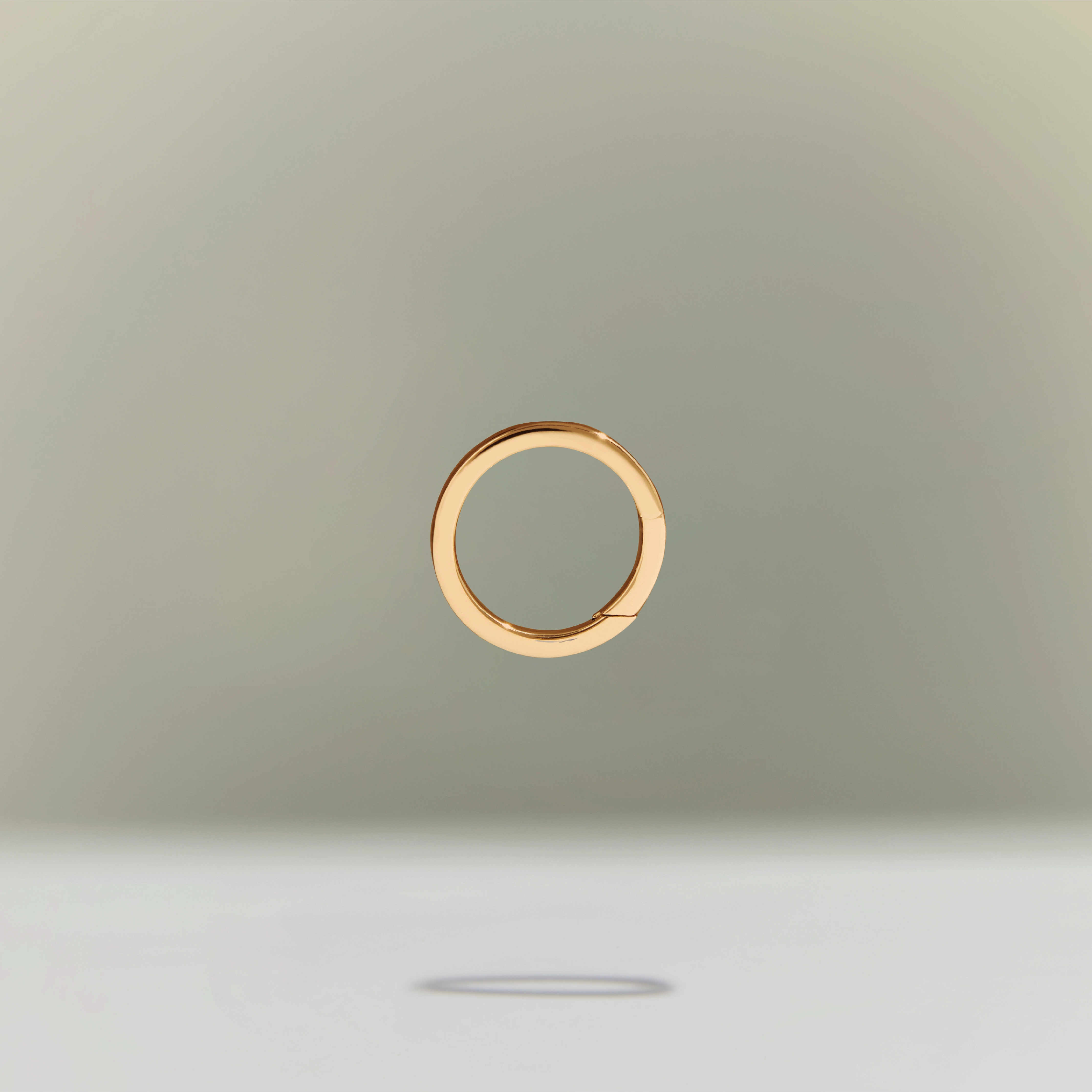 Minimalist gold circular ring floating above a neutral background.