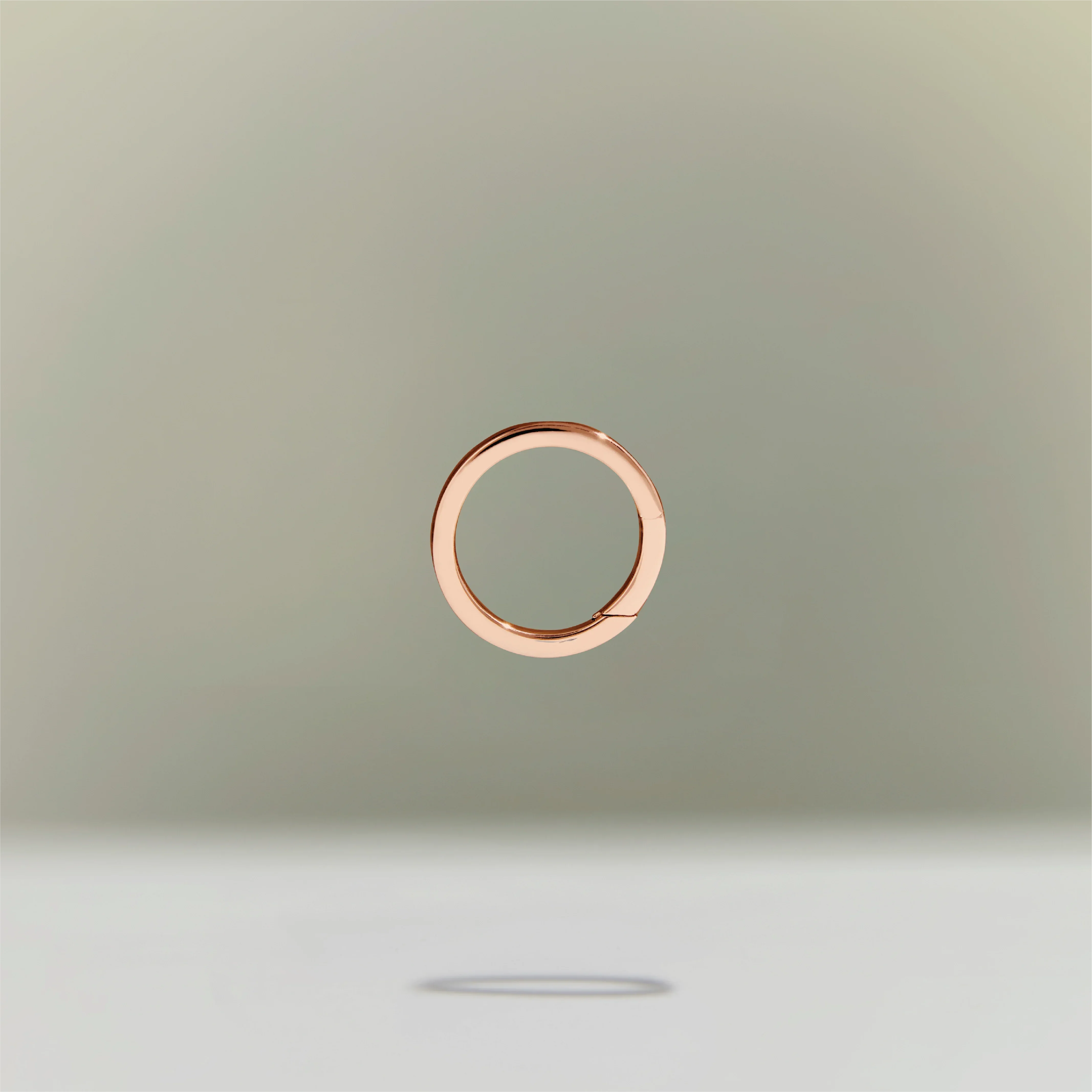 Minimalist rose gold circular ring floating above a neutral background.