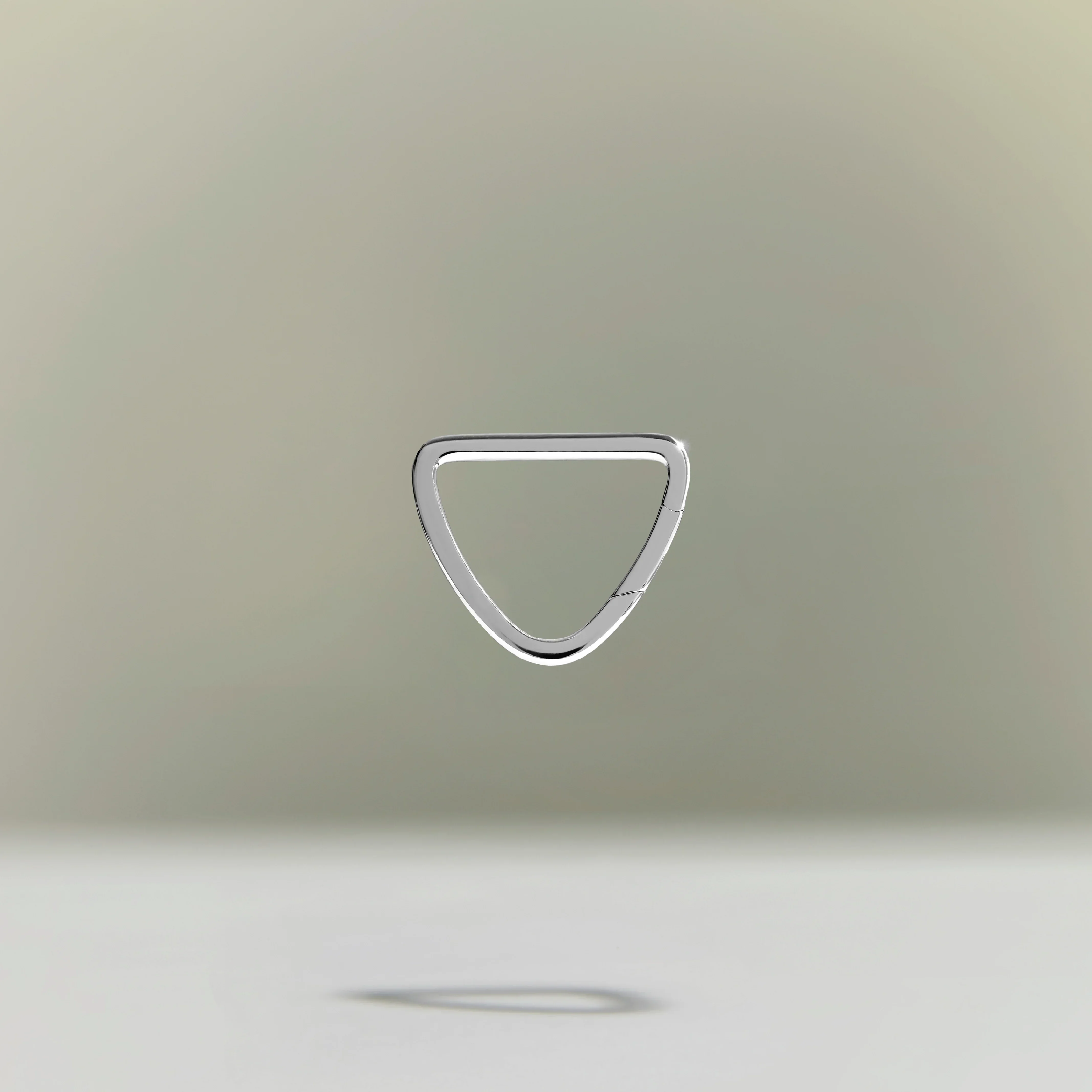Minimalist silver triangular ring floating above a neutral background.