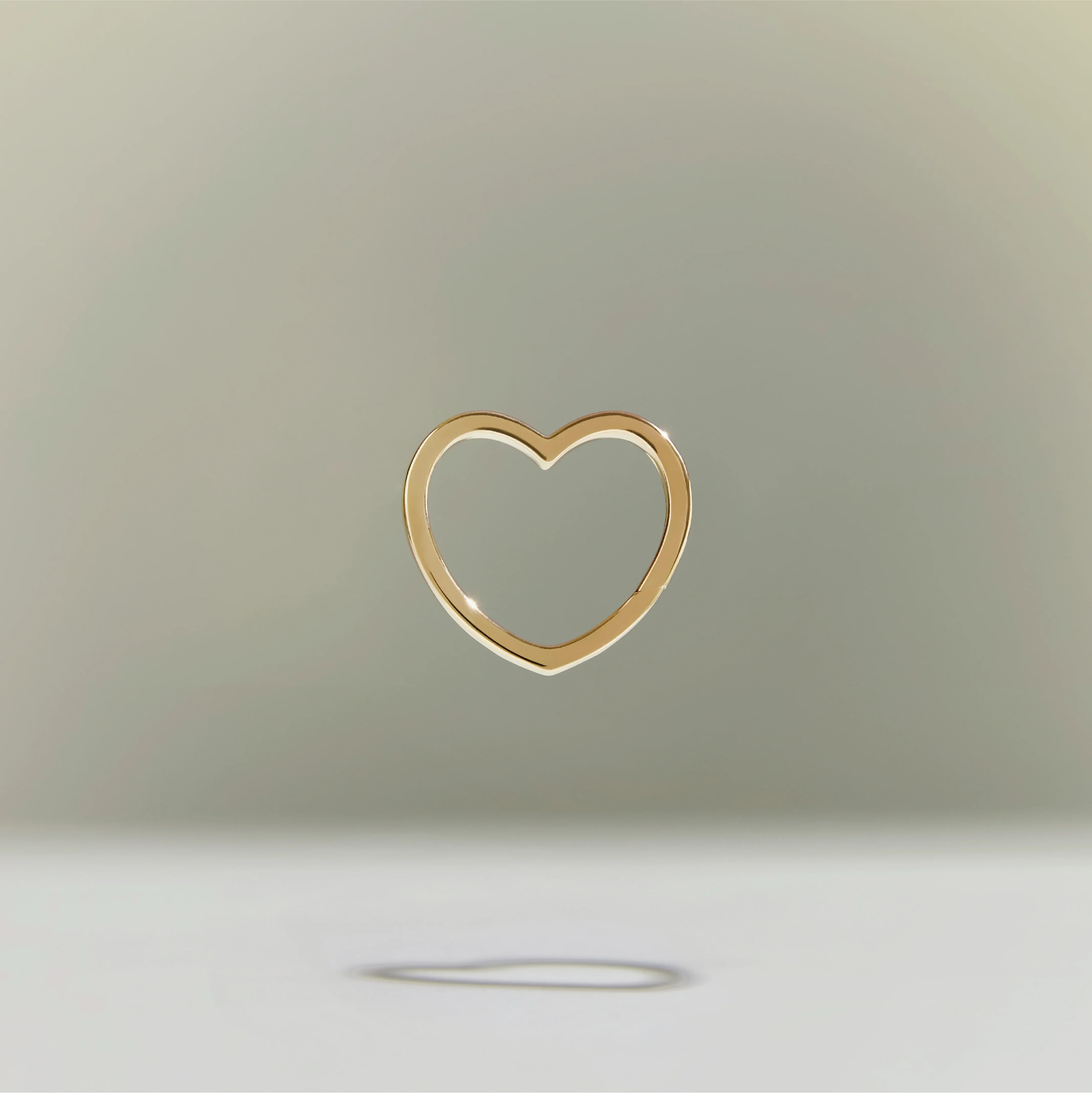 Minimalist gold heart-shaped pendant floating against a soft, neutral background.