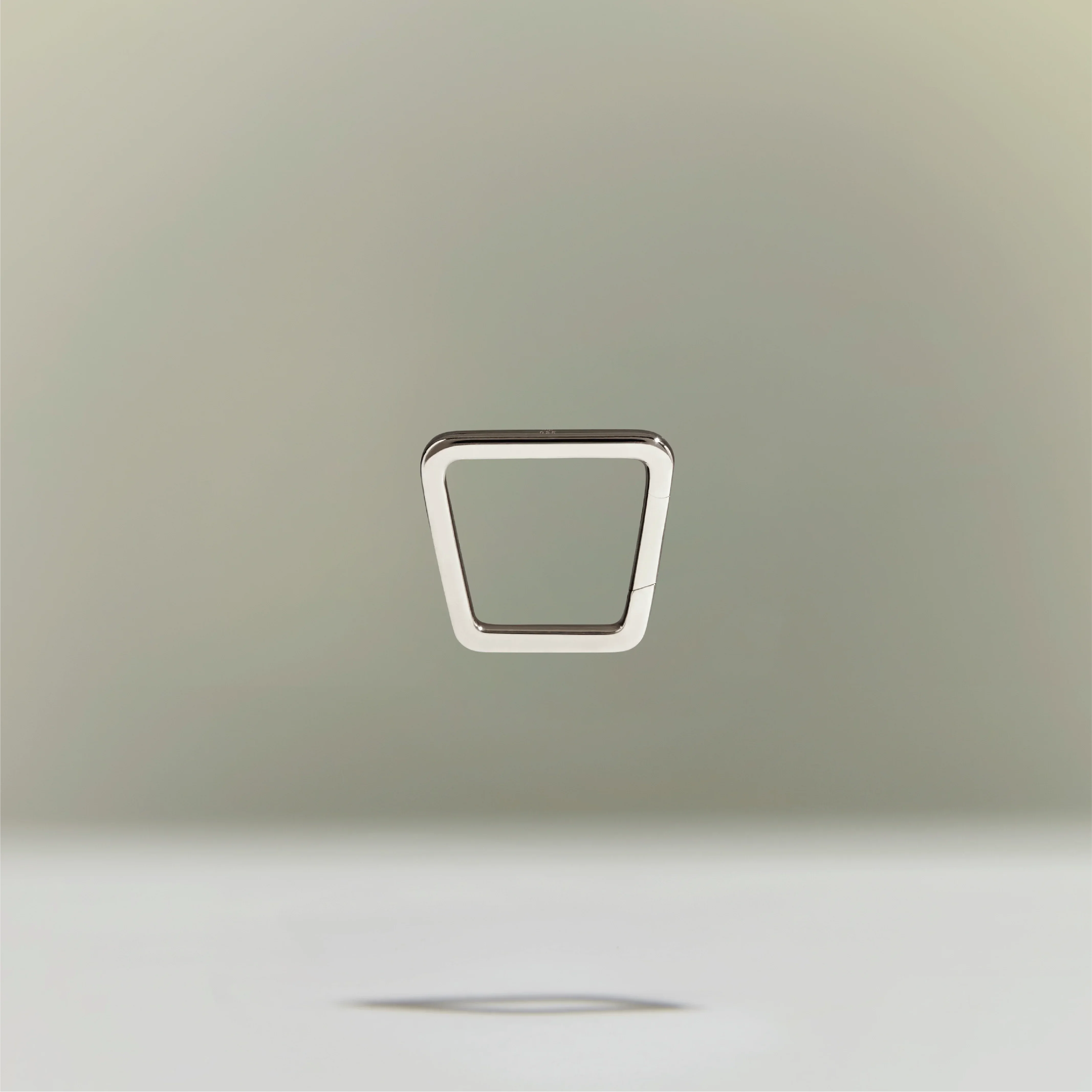 Minimalist silver trapezoid-shaped ring floating above a neutral background.