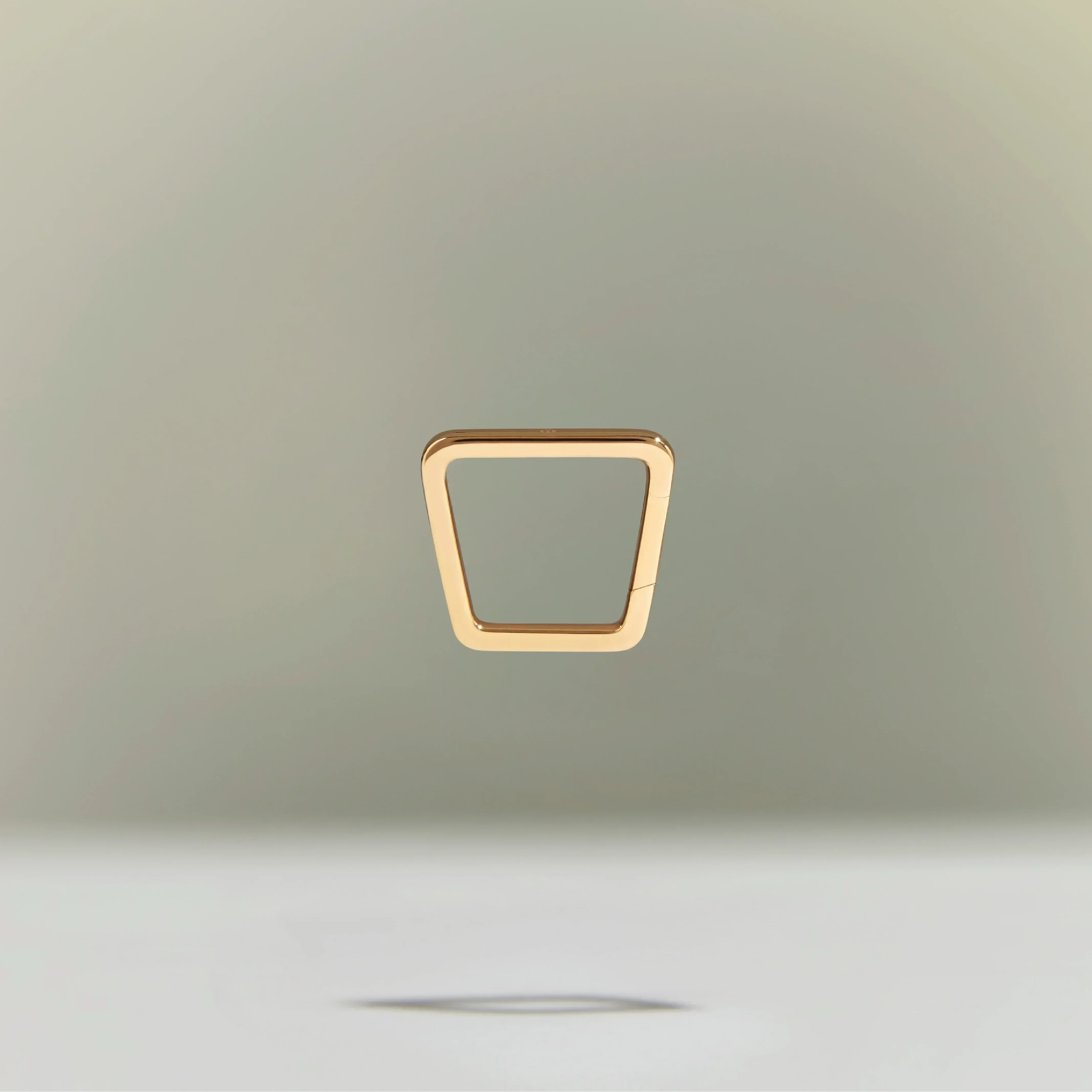 Minimalist gold trapezoid-shaped ring floating above a neutral background.